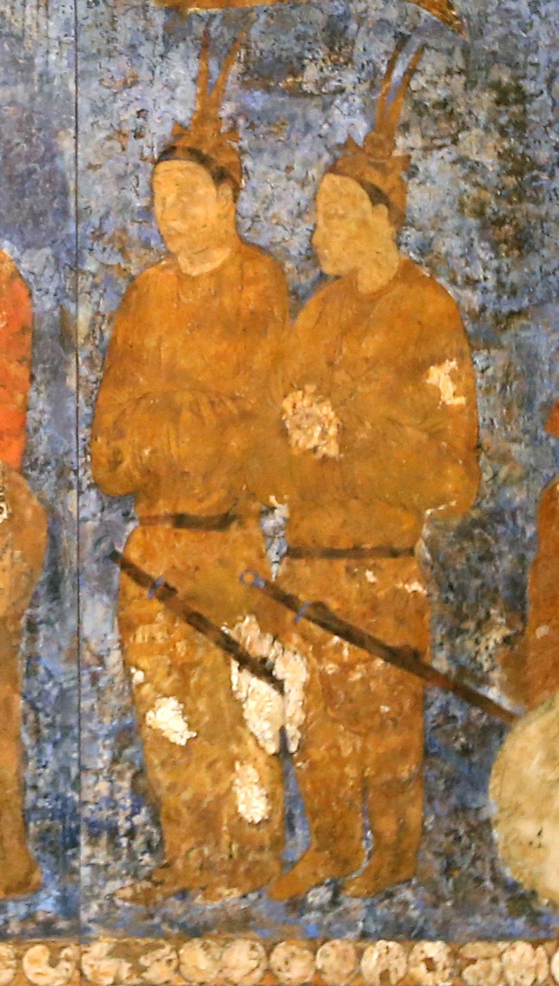 Two envoys at the court of King Varkhuman of Samarkand, usually identified as Goguryeo envoys. Each wears a small cap with two upright bird feathers (jougwan), a long belted coat with tight sleeves, and a ring-pommel sword at the waist.