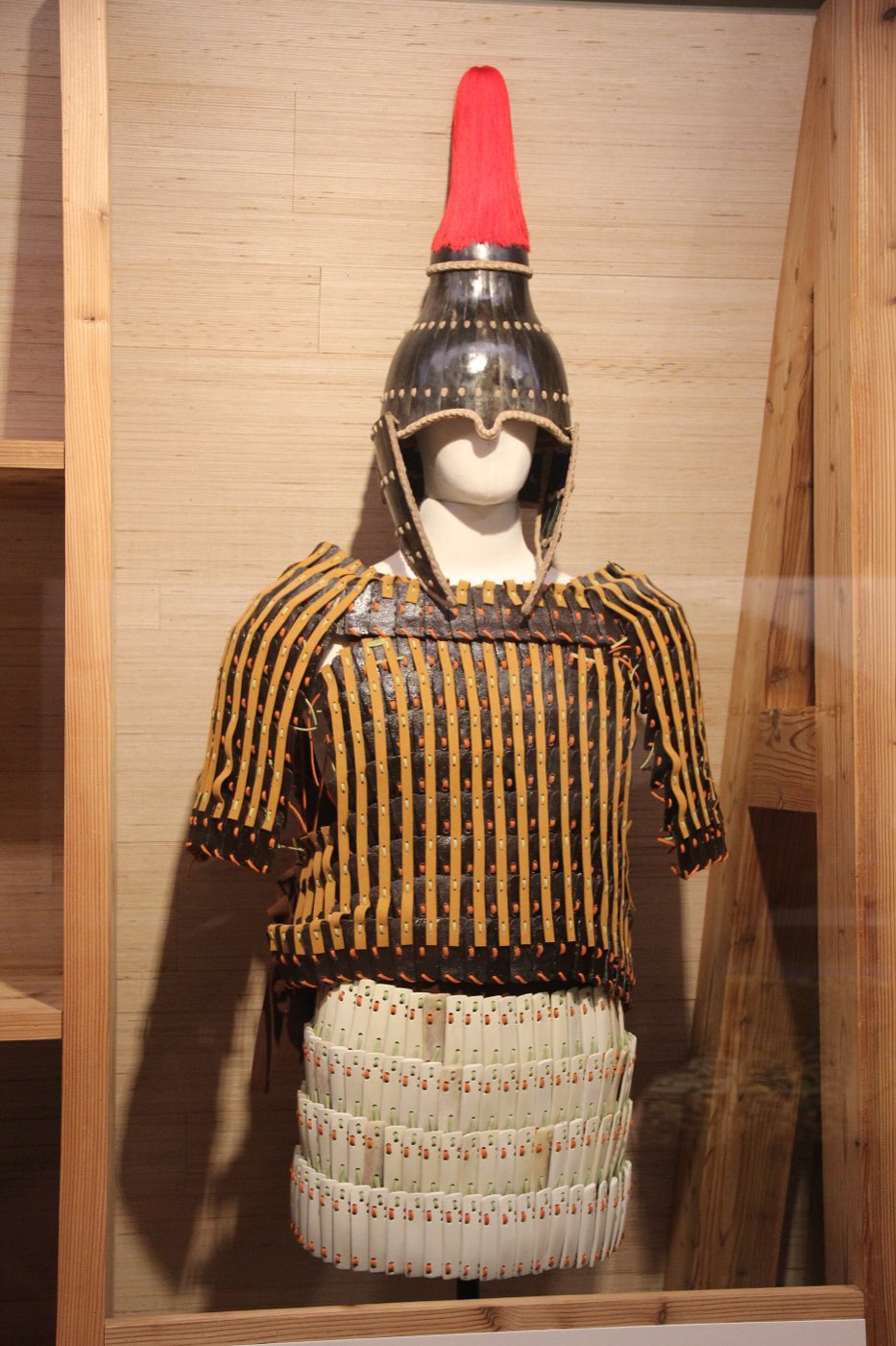 Modern reconstruction of a Baekje helmet with a red plume and a lamellar coat, displayed at the Seoul Baekje Museum. It is a museum model, not an excavated object.