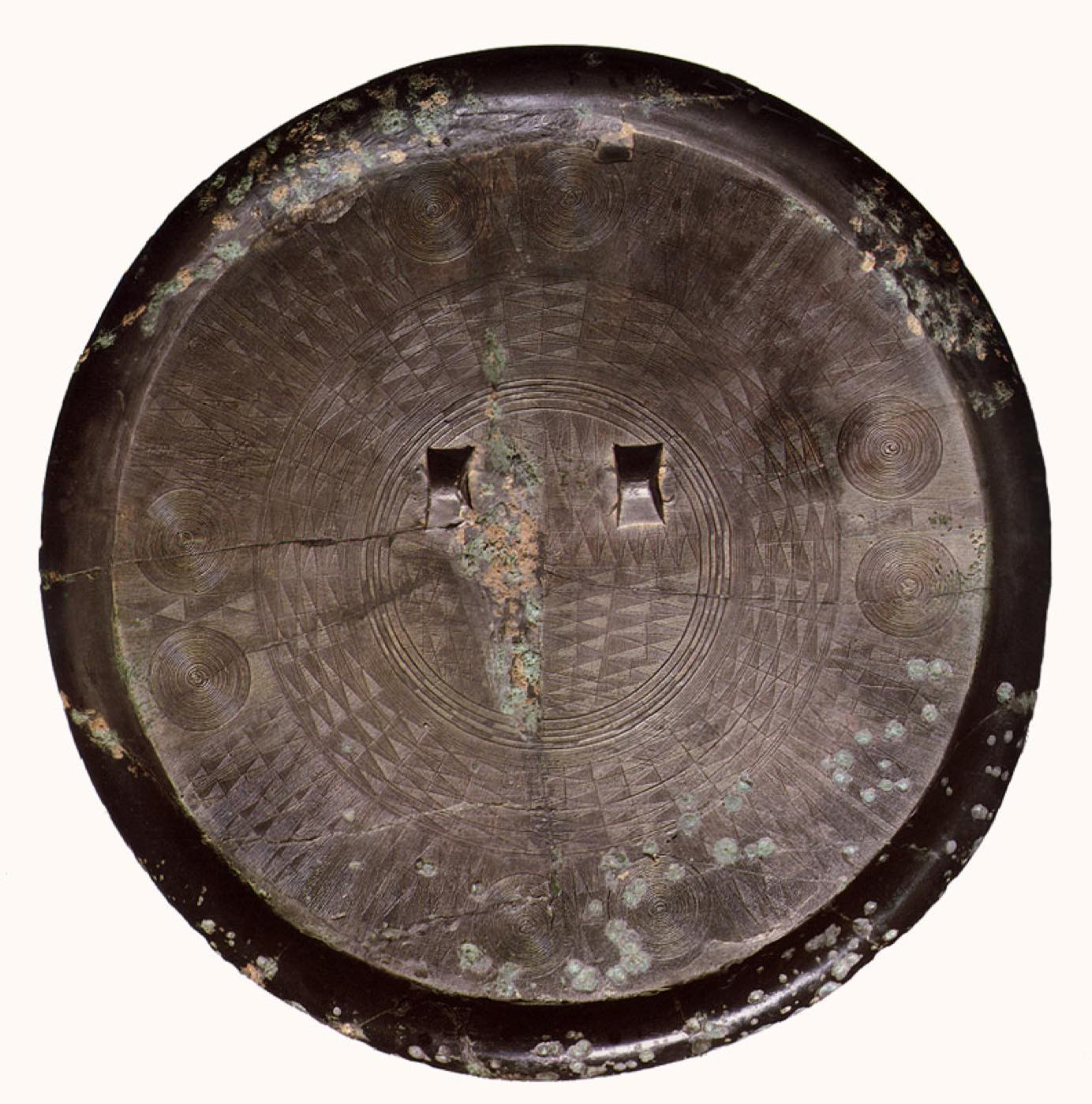 The most refined Korean bronze mirror, its back filled with thousands of hair-thin lines in circles and triangles around two loops. It was cast in the late Bronze Age, in the time of Gojoseon.