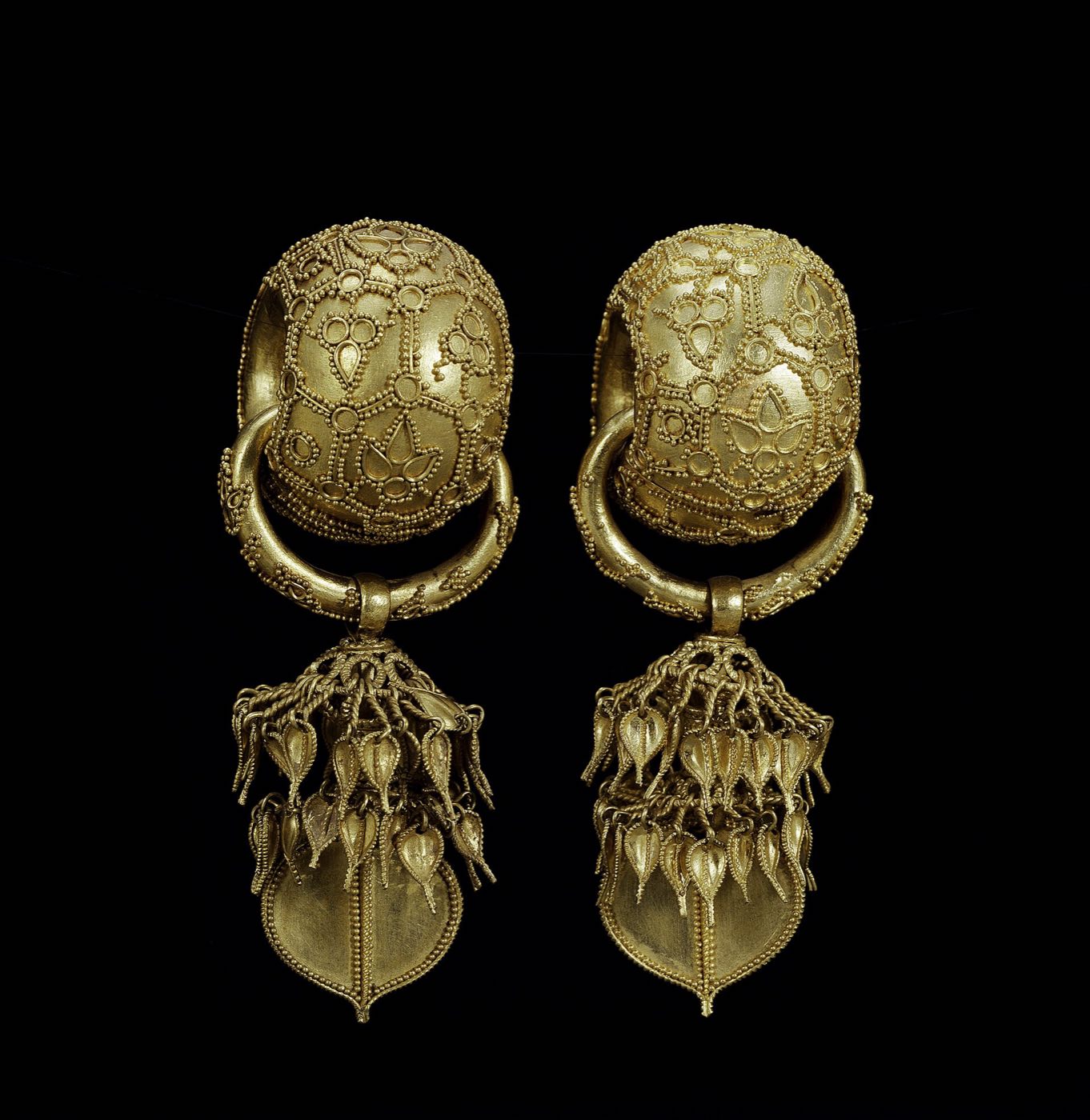 Pair of gold earrings found in 1915 in the Bubuchong (husband-and-wife) tomb in Bomun-dong, Gyeongju. Each has a thick hollow ring covered in fine granulation, with leaf-shaped pendants hanging below; the ring is 3.5 cm across.