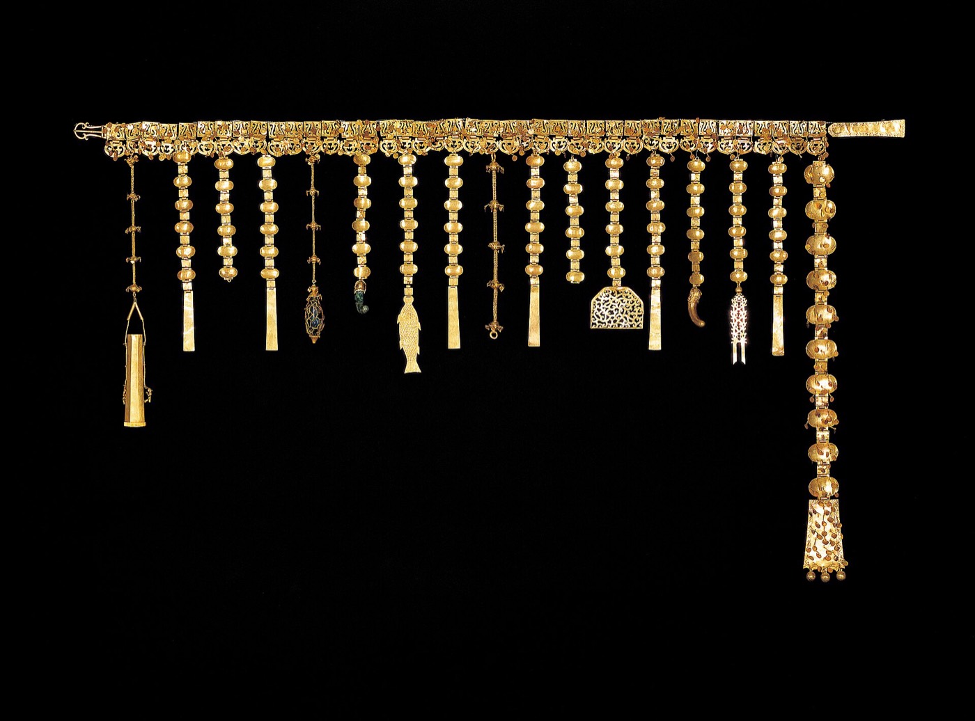 Gold belt from Geumgwanchong with 40 thin gold plaques and 17 pendant strings. The pendants end in a comma-shaped jade, a dragon openwork plaque, a fish and a tiny perfume pouch, symbolic stand-ins for the tools once hung from a horseman’s belt.