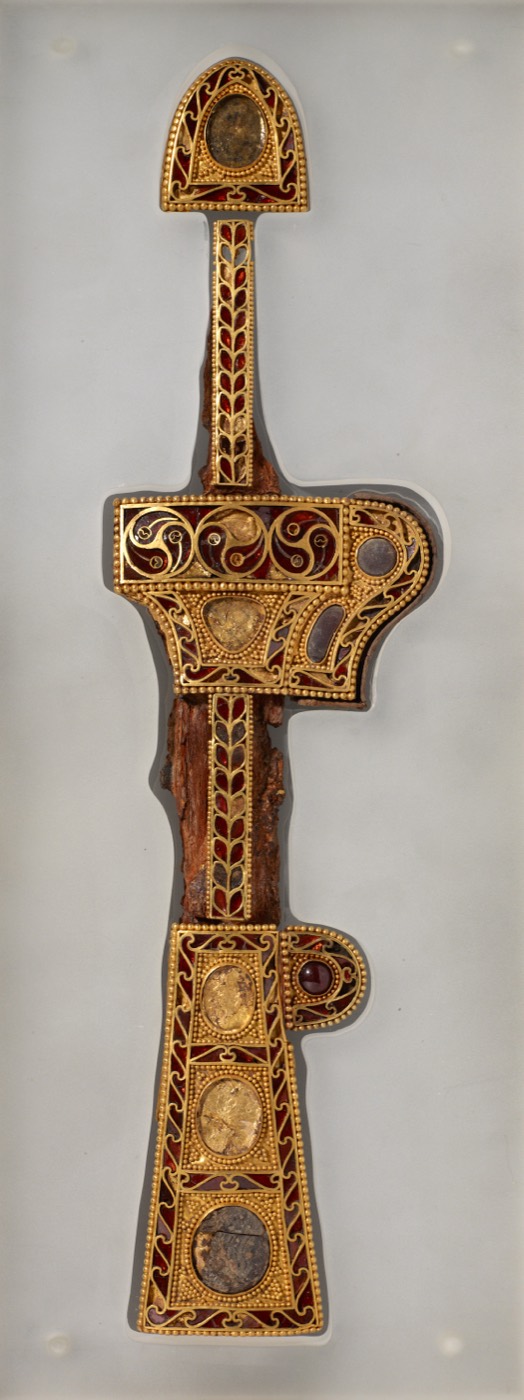 Gold dagger sheath inlaid with garnets in cloisonné, found in Tomb 14 at Gyerim-ro, Gyeongju. Its style comes from Central Asia or the Black Sea region, evidence that Silla’s elite wore imported luxury goods at the belt.