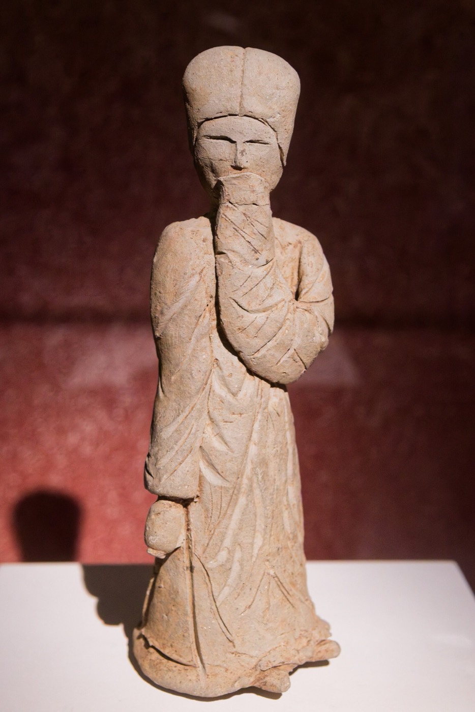 Clay figurine found in 1987 in a stone tomb at Hwangseong-dong, Gyeongju. She holds a bottle in her right hand and raises her wide left sleeve to her mouth as if hiding a smile; her long robe falls to the ground.