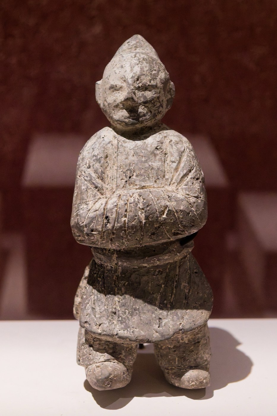 Clay figurine of a military attendant from Yonggang-dong, Gyeongju. He wears a soft hood and a knee-length robe belted over trousers and boots, his hands clasped at the chest in salute.