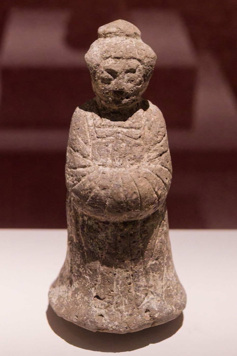 Clay tomb figurine of a woman from a stone-chamber tomb at Yonggang-dong, Gyeongju. Her hair is piled up and her hands are hidden in the sleeves of a long robe, a Tang-influenced dress worn in Silla after the unification wars.
