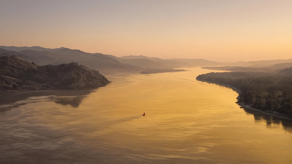 Wide Jolbon river-bend at dawn: one red bow-speck on a gold water-plane
